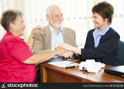Senior couple shakes hands with their financial advisor or broker.