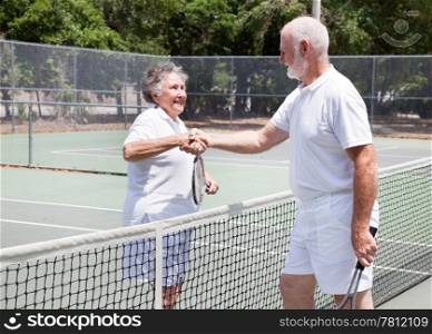 Senior couple shaking hands after their tennis game.