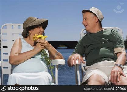 Senior couple sitting at the lakeside and looking at each other
