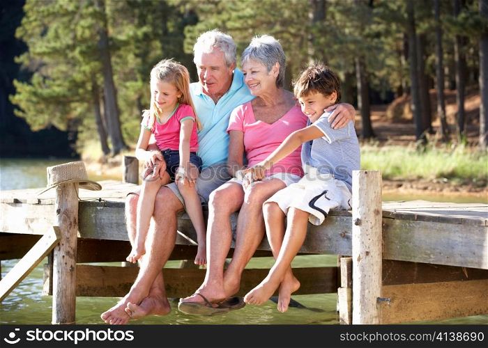 Senior couple sitting by lake with grandchildren