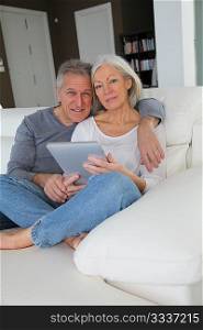 Senior couple sitting in sofa with electronic tablet
