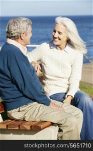 Senior Couple Sitting On Bench By Sea Together