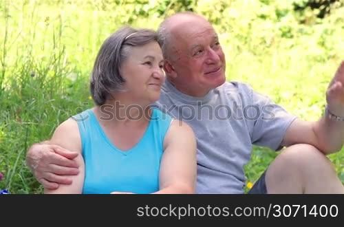 Senior couple sitting on grass together relaxing and enjoying the nature.