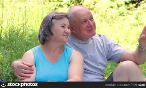 Senior couple sitting on grass together relaxing and enjoying the nature.