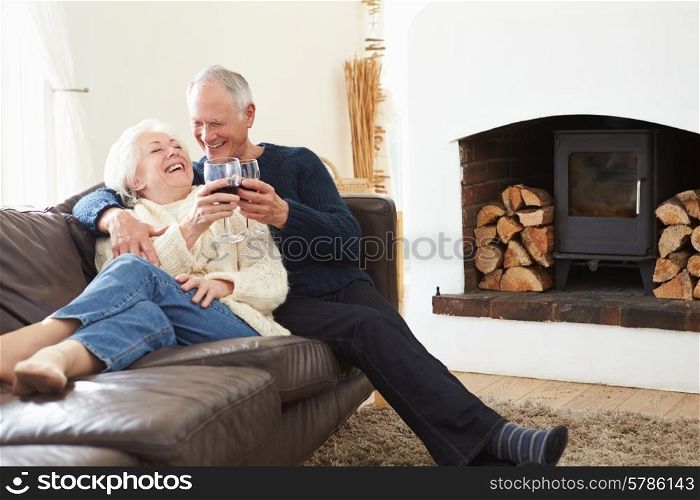 Senior Couple Sitting On Sofa Drinking Red Wine