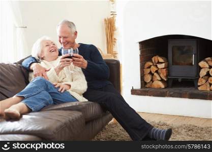 Senior Couple Sitting On Sofa Drinking Red Wine