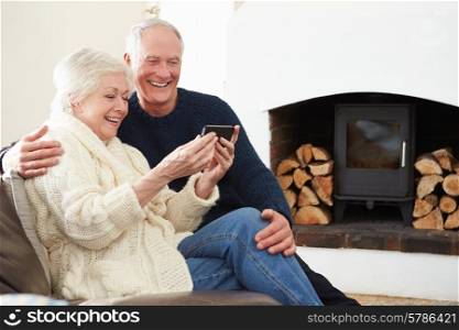 Senior Couple Sitting On Sofa Taking Selfie