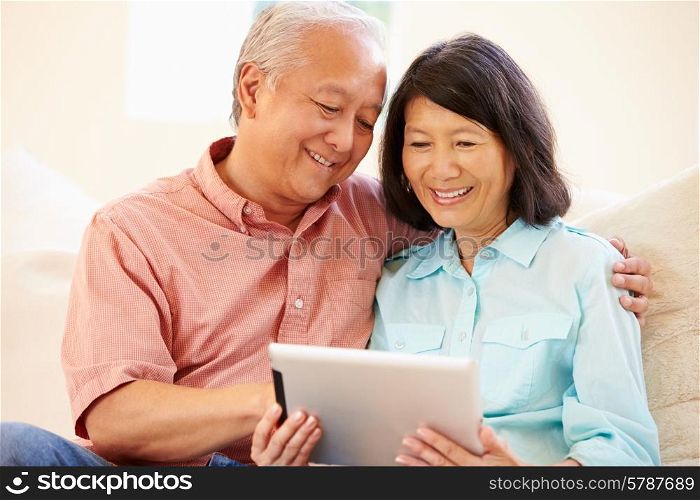 Senior Couple Sitting On Sofa Using Digital Tablet