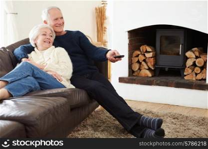 Senior Couple Sitting On Sofa Watching TV