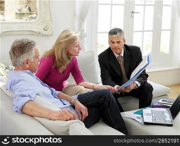 Senior couple sitting on sofa with financial advisor elevated view