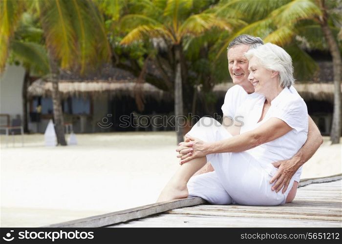 Senior Couple Sitting On Wooden Jetty