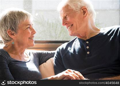 Senior couple sitting together, face to face, smiling