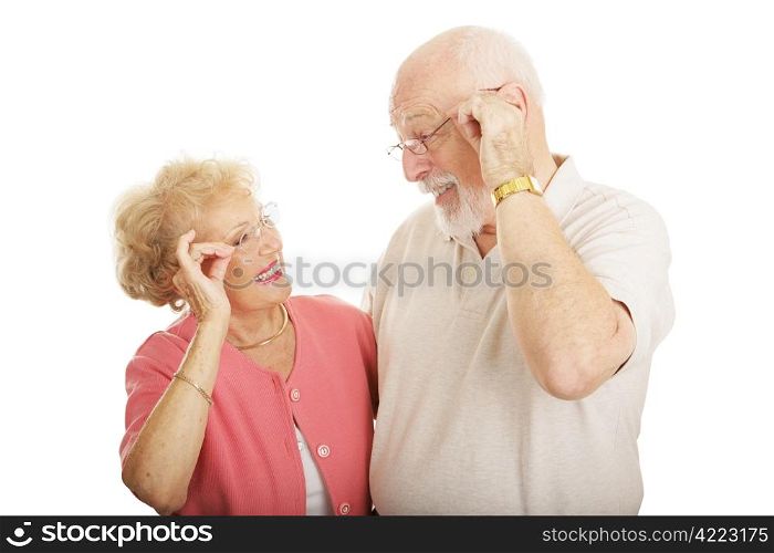 Senior couple smiling and looking at each other&rsquo;s new glasses. Isolated on white.