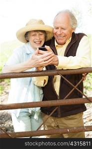 Senior couple smiling at message on mobile phone