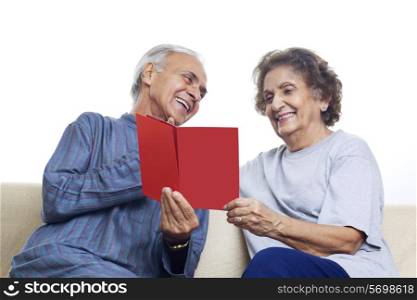 Senior couple smiling while looking at card