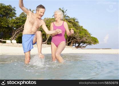 Senior Couple Splashing In Sea On Tropical Beach Holiday