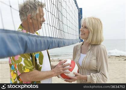 Senior couple stand at volleyball net