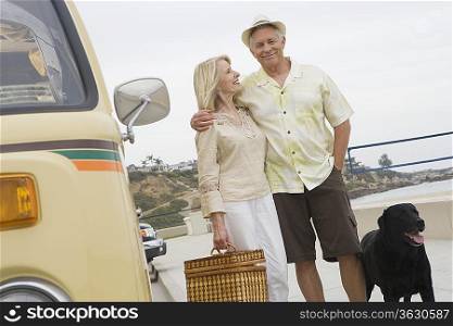 Senior couple stand on beach promenade with campervan