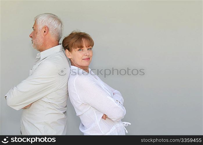Senior couple standing back to back