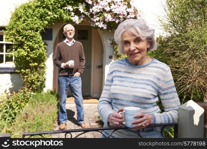 Senior Couple Standing In Cottage Garden With Coffee Cups