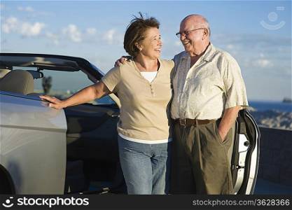 Senior couple standing in front of car