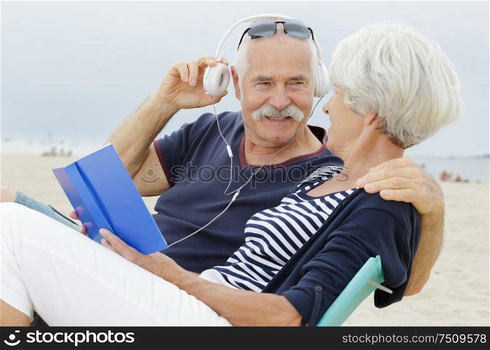 senior couple standing on beach listening to mp3 player