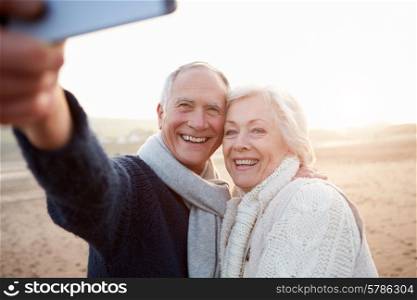 Senior Couple Standing On Beach Taking Selfie