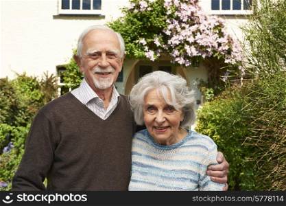 Senior Couple Standing Outside Pretty Cottage
