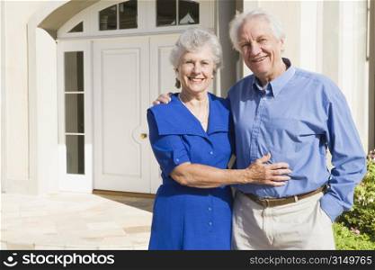Senior couple standing outside their home