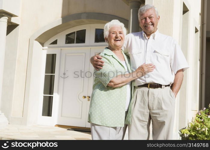 Senior couple standing outside their home