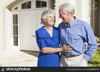 Senior couple standing outside their home