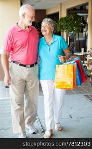 Senior couple strolling along with their shopping bags.