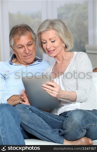 Senior couple surfing on internet with electronic tablet
