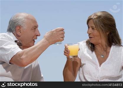 Senior couple toasting with glasses of juice and smiling
