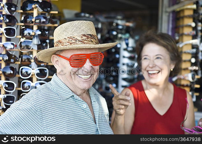 Senior couple trying on sunglasses, smiling