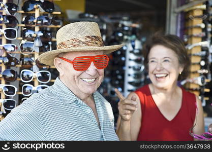 Senior couple trying on sunglasses, smiling