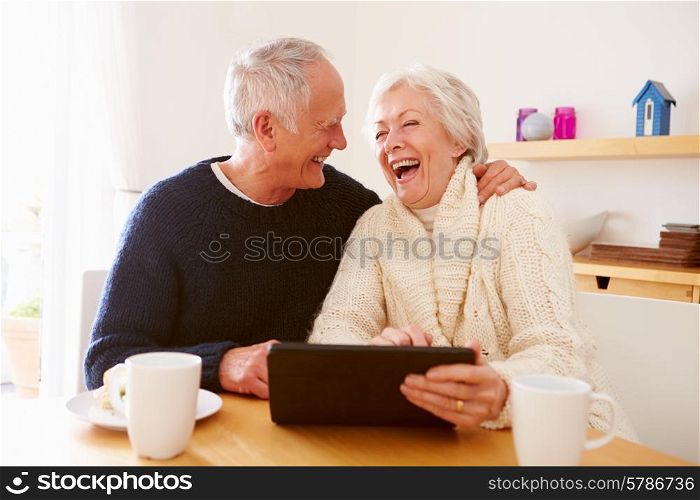 Senior Couple Using Digital Tablet At Table
