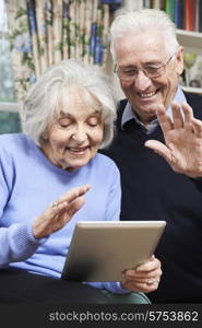 Senior Couple Using Digital Tablet For Video Call With Family