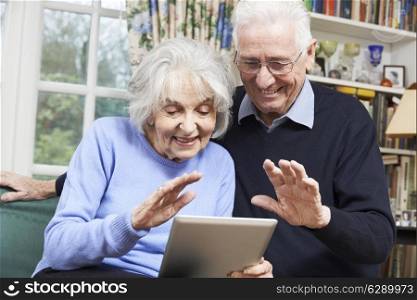 Senior Couple Using Digital Tablet For Video Call With Family