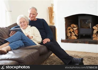 Senior Couple Using Digital Tablet On Sofa