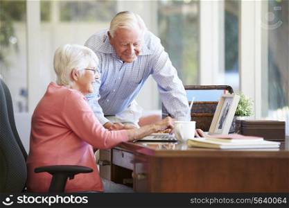 Senior Couple Using Laptop On Desk At Home