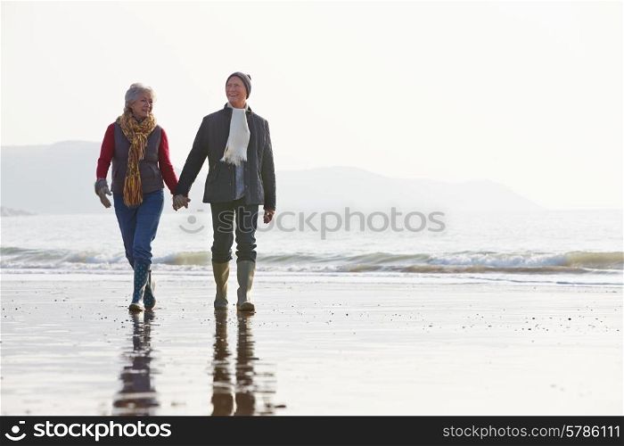 Senior Couple Walking Along Winter Beach