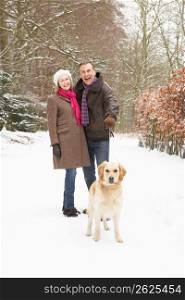 Senior Couple Walking Dog Through Snowy Woodland
