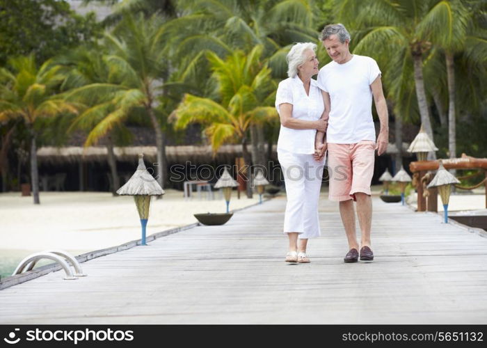 Senior Couple Walking On Wooden Jetty