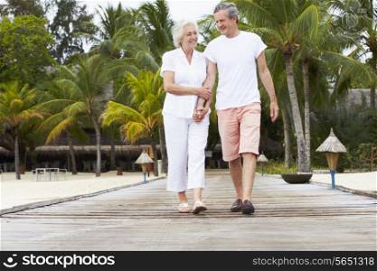 Senior Couple Walking On Wooden Jetty
