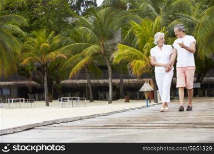 Senior Couple Walking On Wooden Jetty