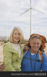 Senior couple with backpack near wind farm