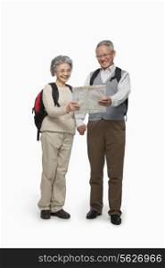 Senior couple with backpacks checking map