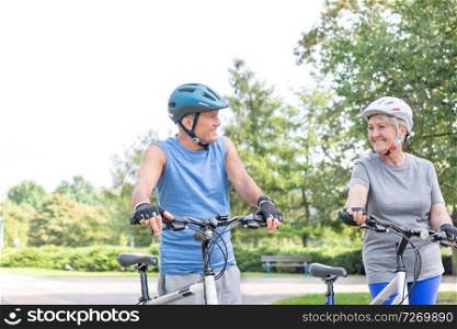 Senior couple with bicycles looking at each other in park