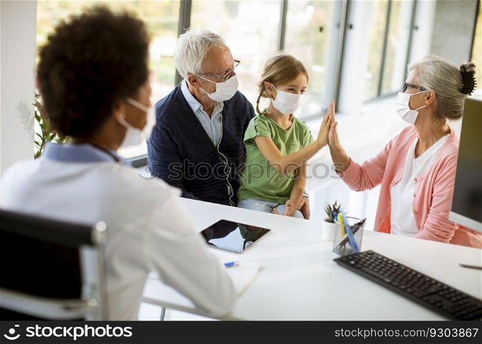 Senior couple with cute grandaughter black female doctor in the office